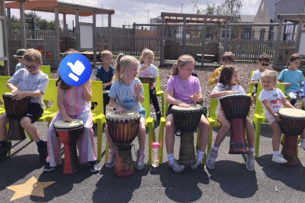Children taking part in a drumming workshop at Playtime Paradise summer holiday club.